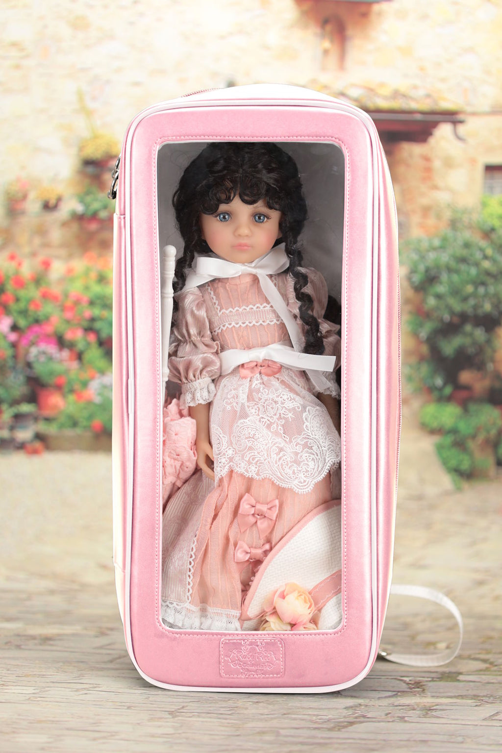 Doll in a pink carrying case with a garden background