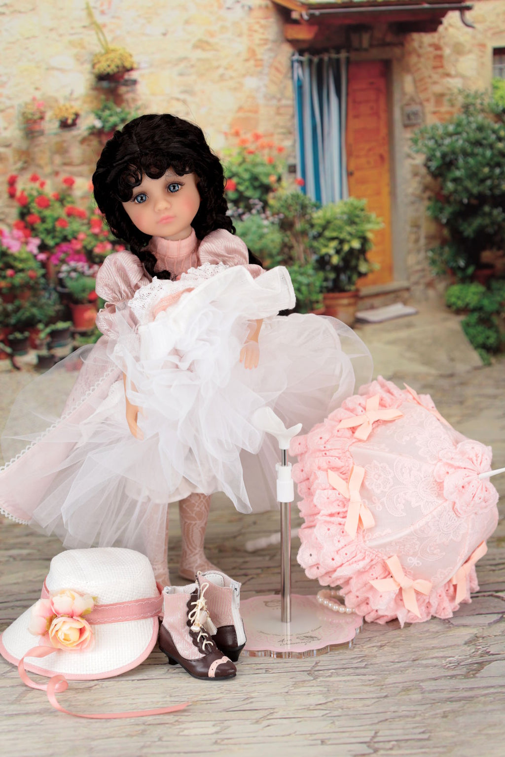 Doll in a white dress with accessories on a wooden floor outdoors.