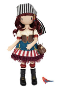 A stylized pirate Gorjuss doll with a black-and-white striped hat, burgundy hair, a cream blouse, brown vest, blue skirt panel, red-and-white striped skirt, black boots, and a small brown purse. A small red-and-blue bird figurine appears at the lower right on a plain white background.