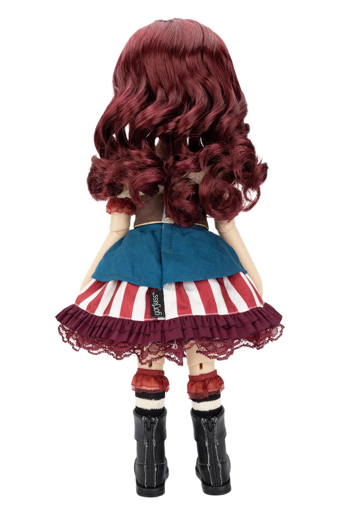 A Gorjuss doll viewed from the back, featuring long, wavy burgundy hair, a blue denim-style top, a red and white striped skirt with a burgundy lace ruffle, red-and-white striped socks, and black boots, set against a plain white background.