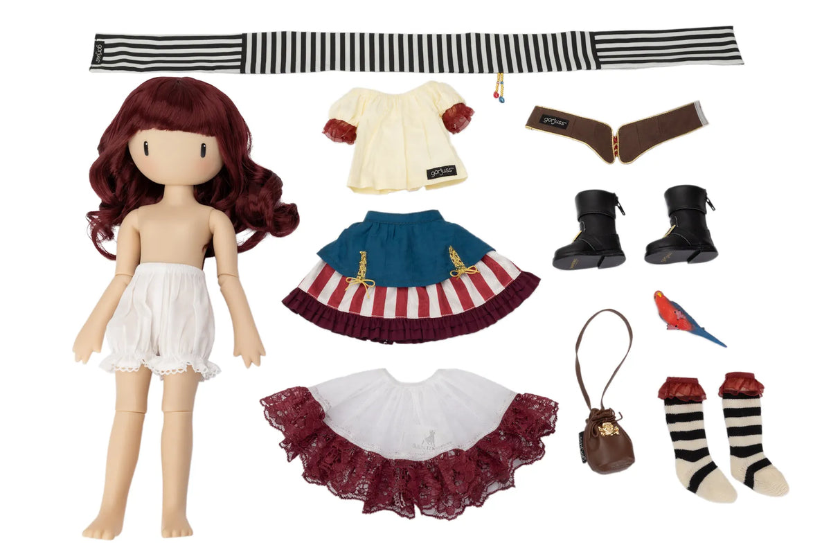A Gorjuss doll set displayed on a white background, featuring a doll with long burgundy hair and a white ruffled skirt, along with multiple clothing and accessory pieces including a striped headband, cream top, blue skirt with red-and-white stripes, black boots, a white-and-red ruffled skirt, a small brown handbag, striped socks, and a small red-and-blue bird accessory.