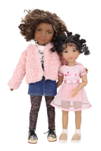 Maya and Minnie, one with a pink fur coat and the other in a pink dress, standing together on a white background.