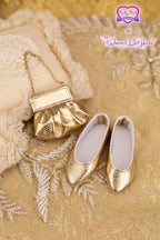 Gold doll shoes and handbag on a textured gold surface