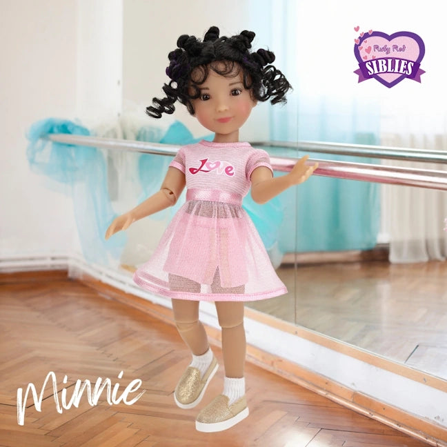 Doll in a pink outfit with 'Love' on it, standing in a dance studio.