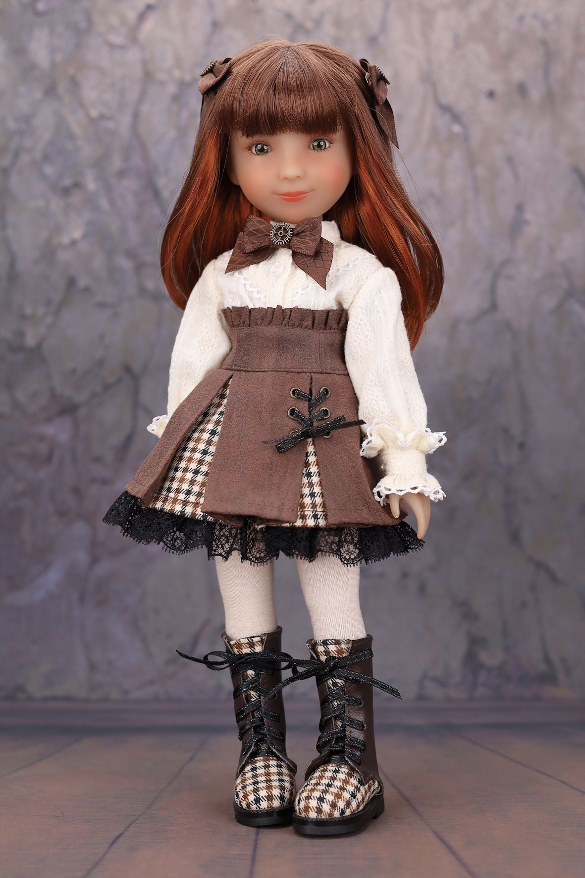 Doll with brown hair and outfit standing against a textured gray background