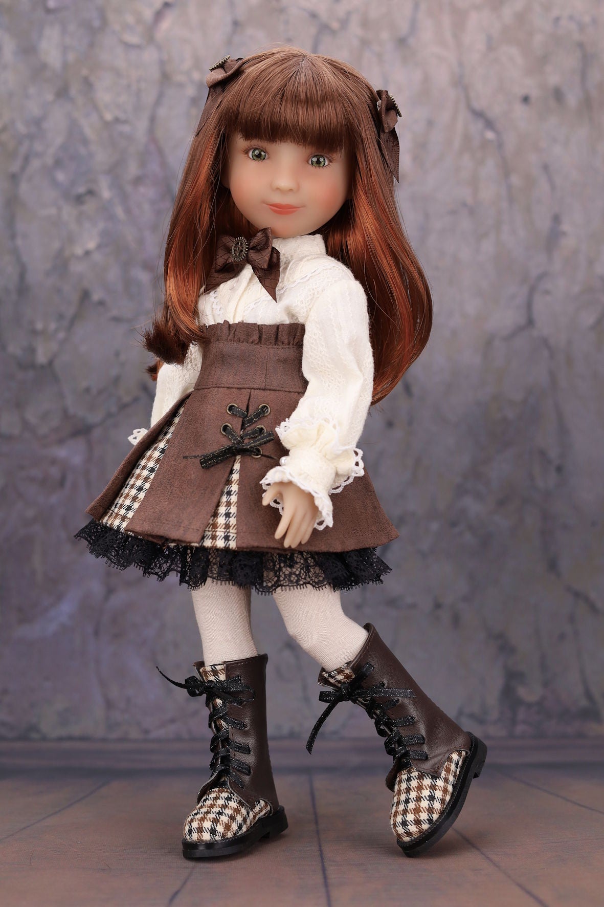 Doll with brown hair and outfit standing against a textured gray background