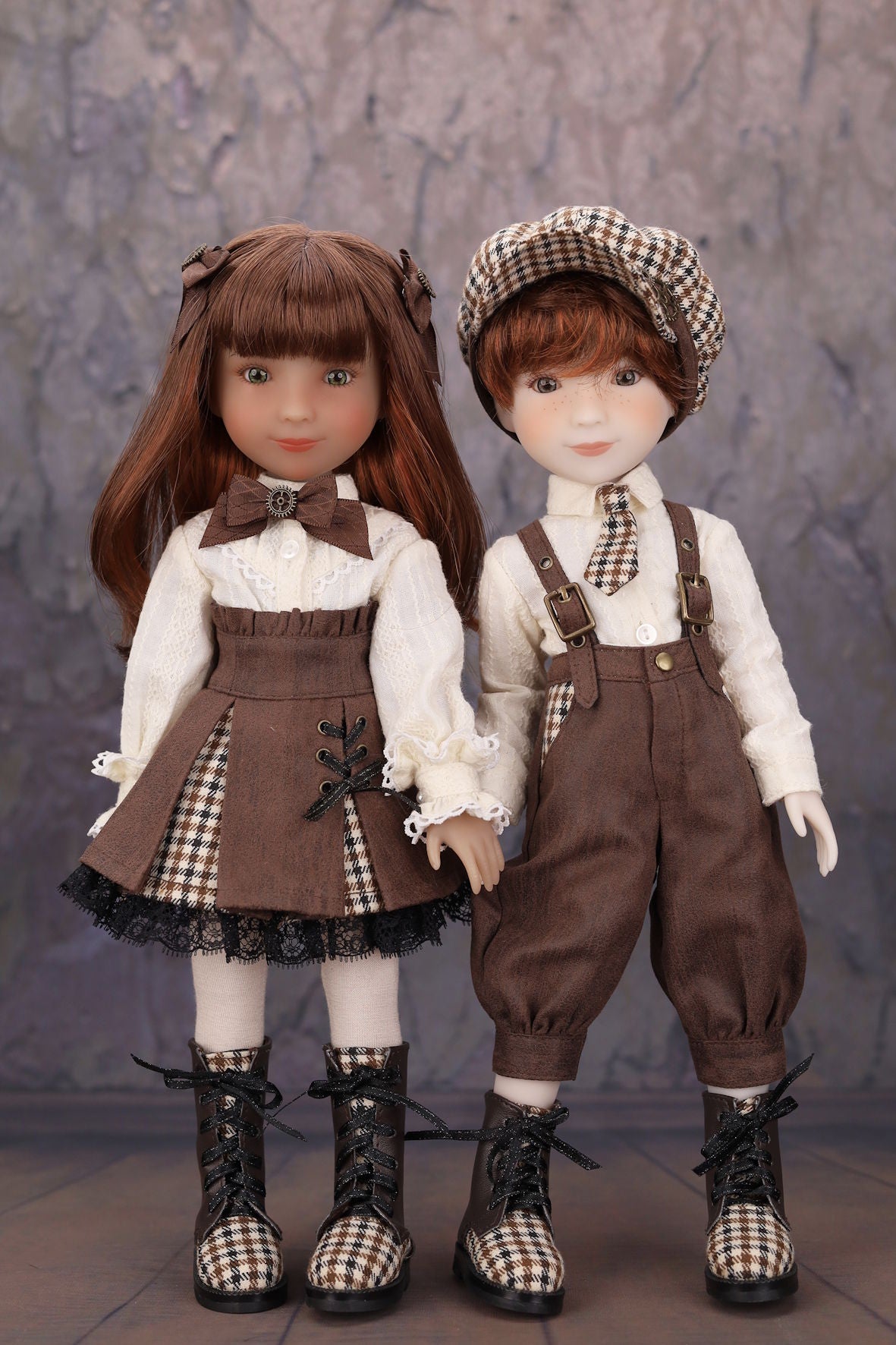 Two dolls in vintage-style outfits with checkered patterns against a neutral background