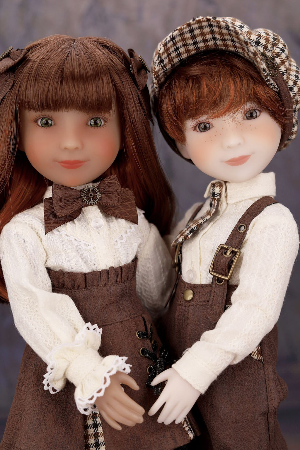 Two dolls in vintage-style clothing with a plain background