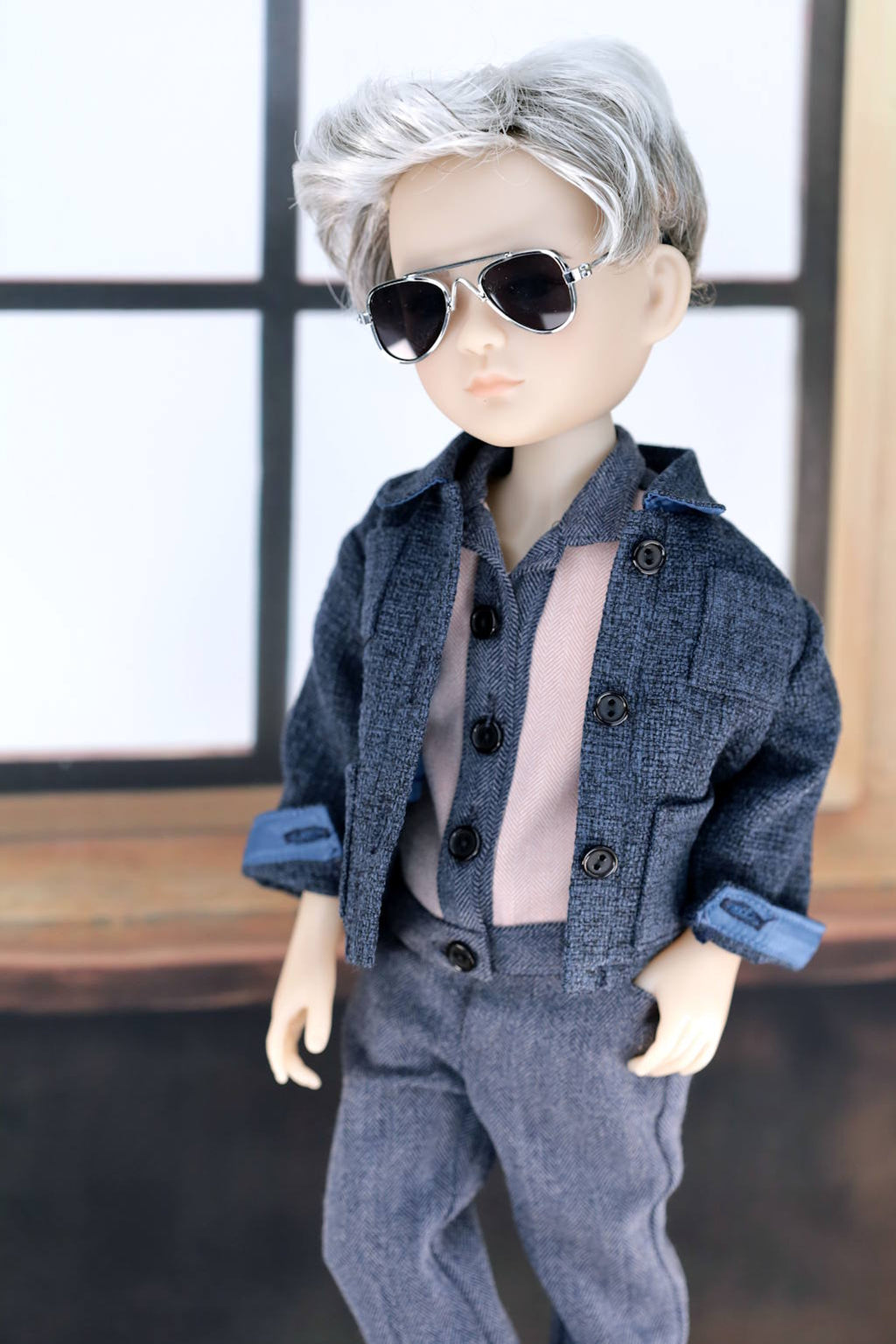 Doll wearing a blue outfit with sunglasses against a neutral background