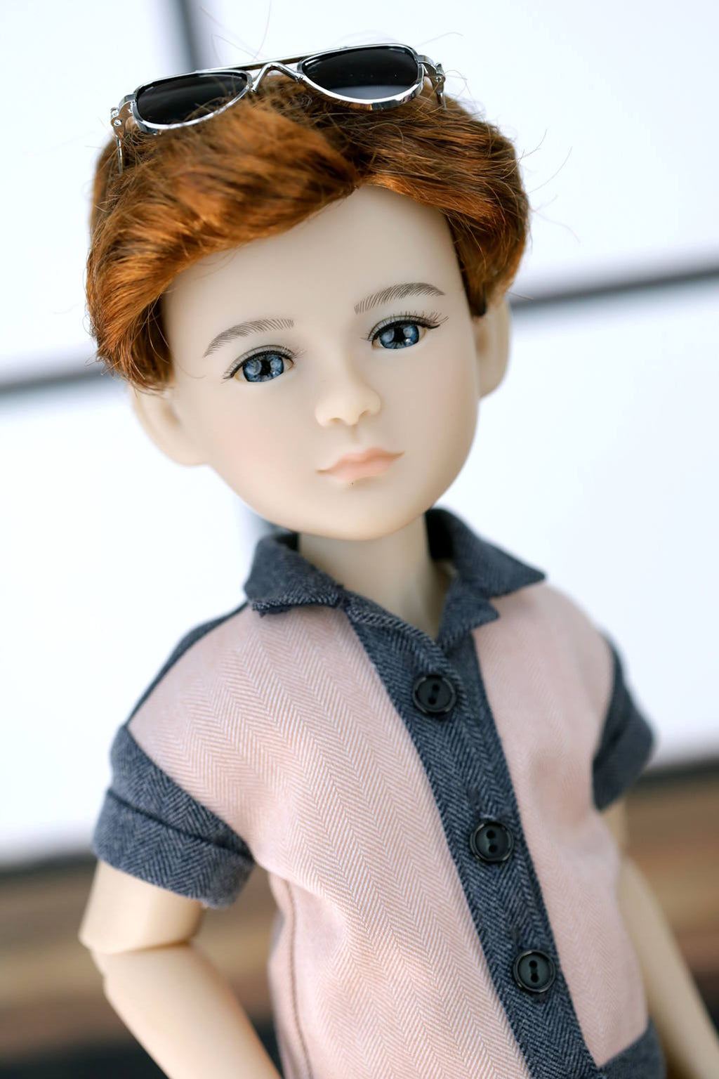 Doll with red hair and sunglasses on head, wearing a gray shirt with sheer overlay.