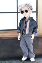 Doll wearing a blue outfit with sunglasses in a room with large windows.