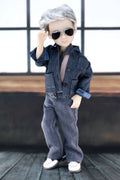 Doll wearing a denim outfit with sunglasses against a window background