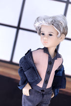Doll with gray hair and a dark outfit in front of a window