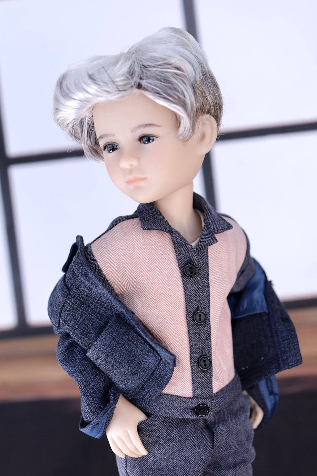 Doll with gray hair wearing a dark blue outfit against a neutral background