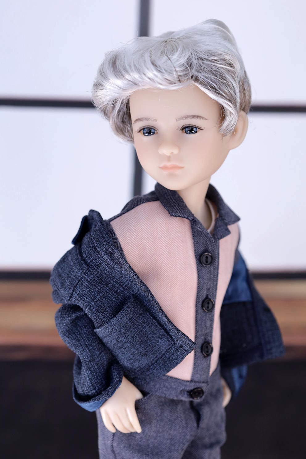 Doll with gray hair and gray outfit against a blurred background