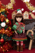 Doll in festive outfit holding a gift box with Christmas decorations in the background