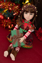 Doll in festive outfit with gift in front of Christmas tree