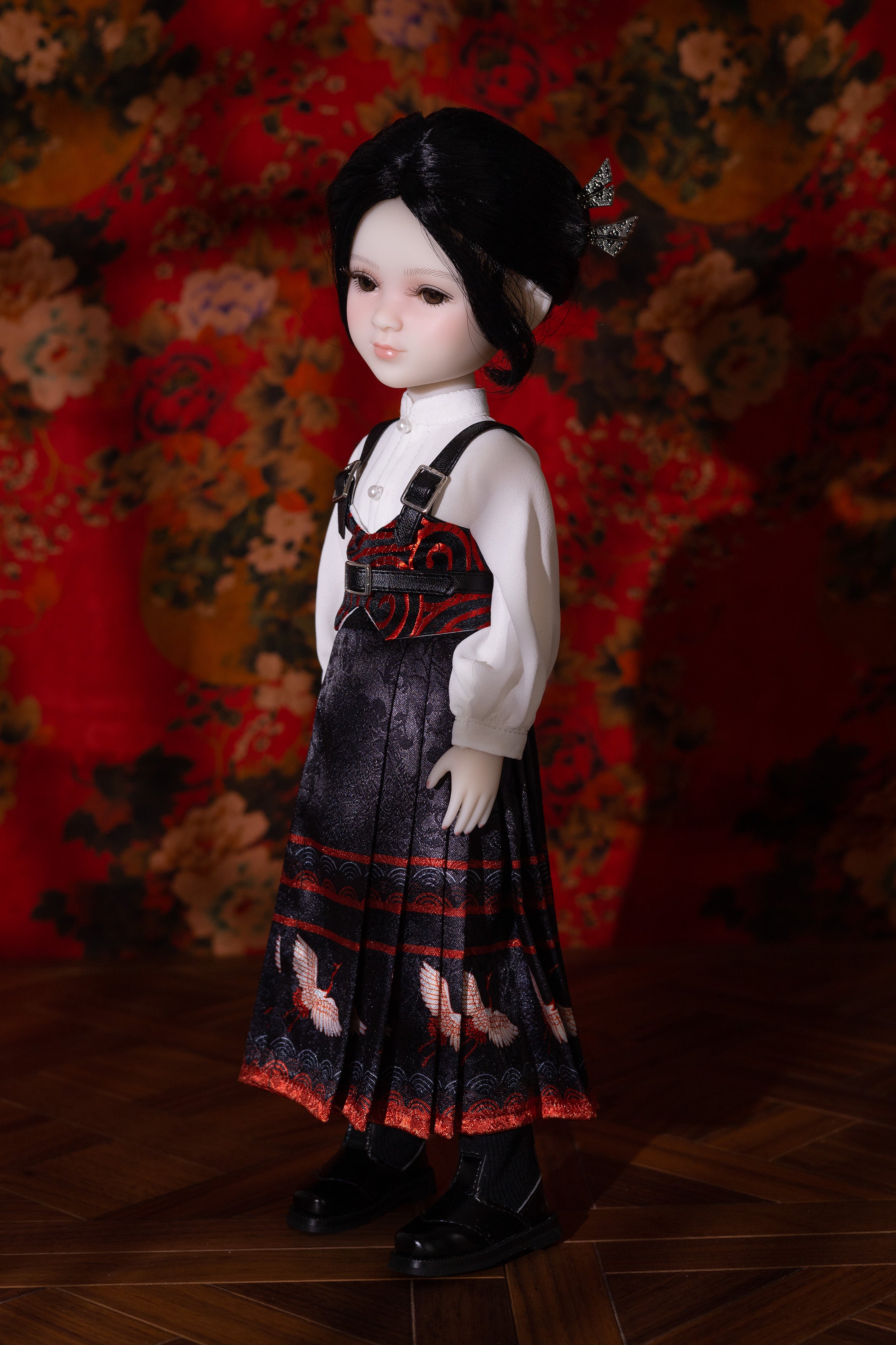 Doll wearing a black dress with red patterns against a floral background