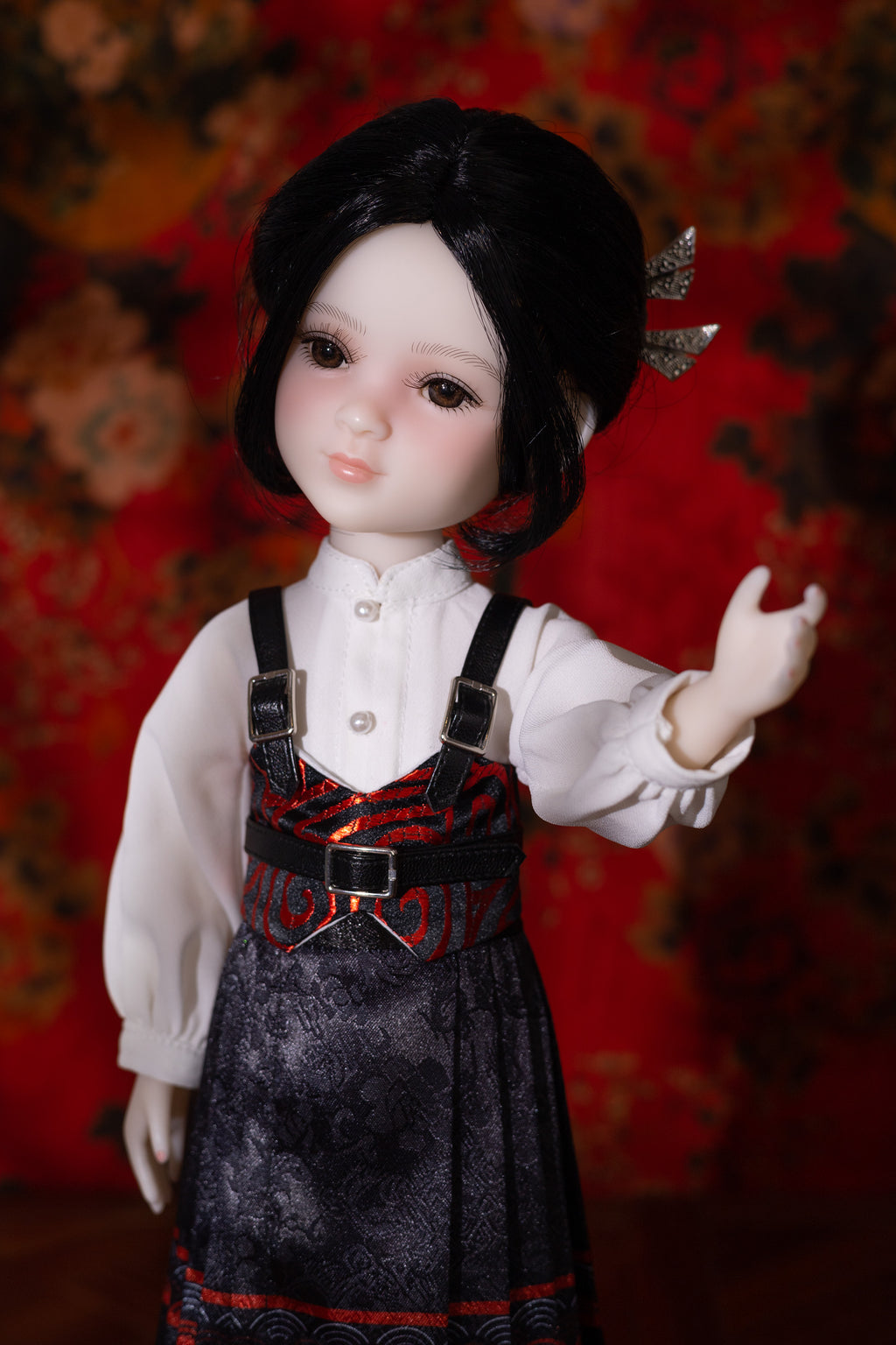 Doll with black hair and a detailed outfit against a red floral background