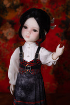 Doll with black hair and a detailed outfit against a red floral background