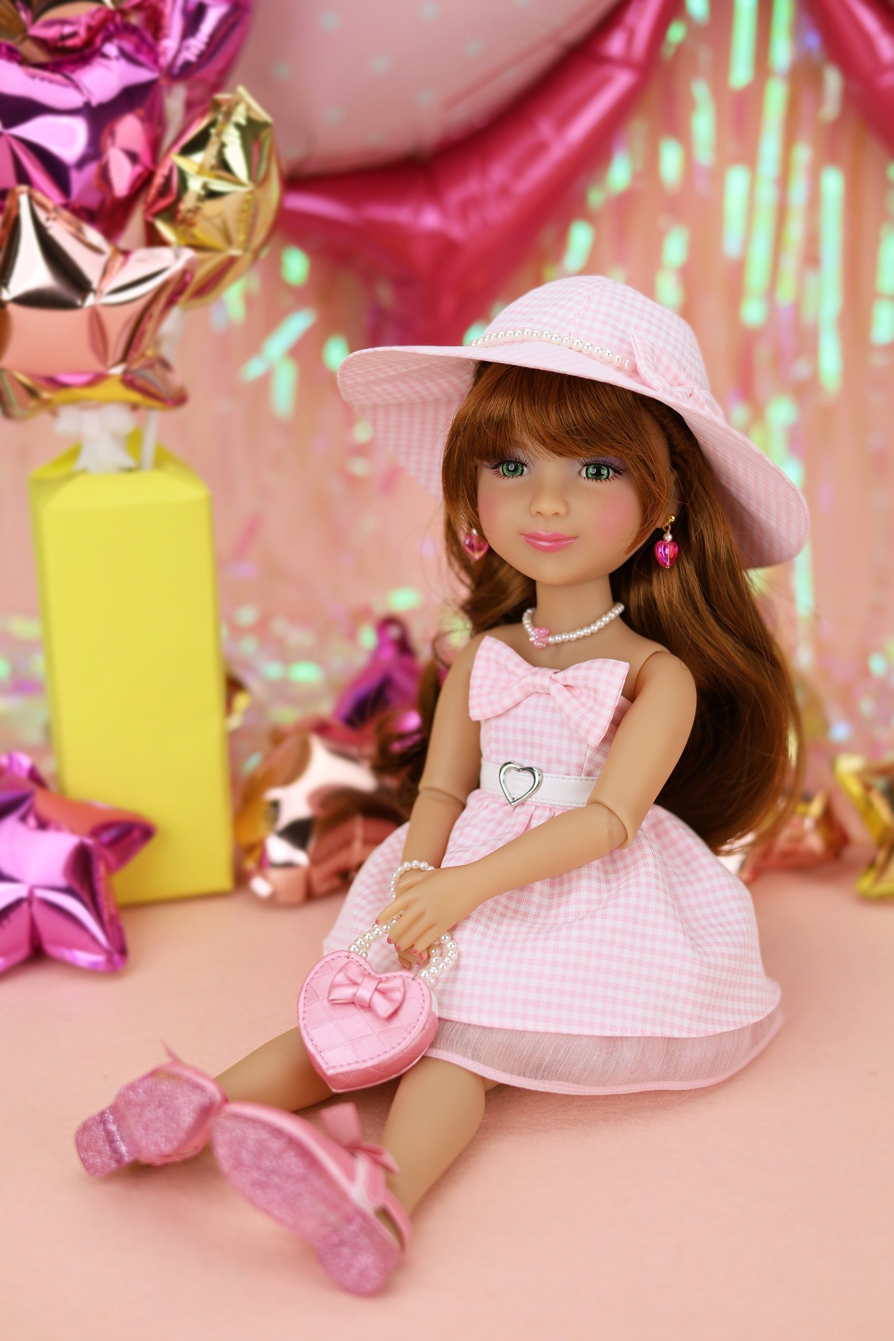 Doll in a pink dress and hat surrounded by colorful balloons and gifts on a pink background