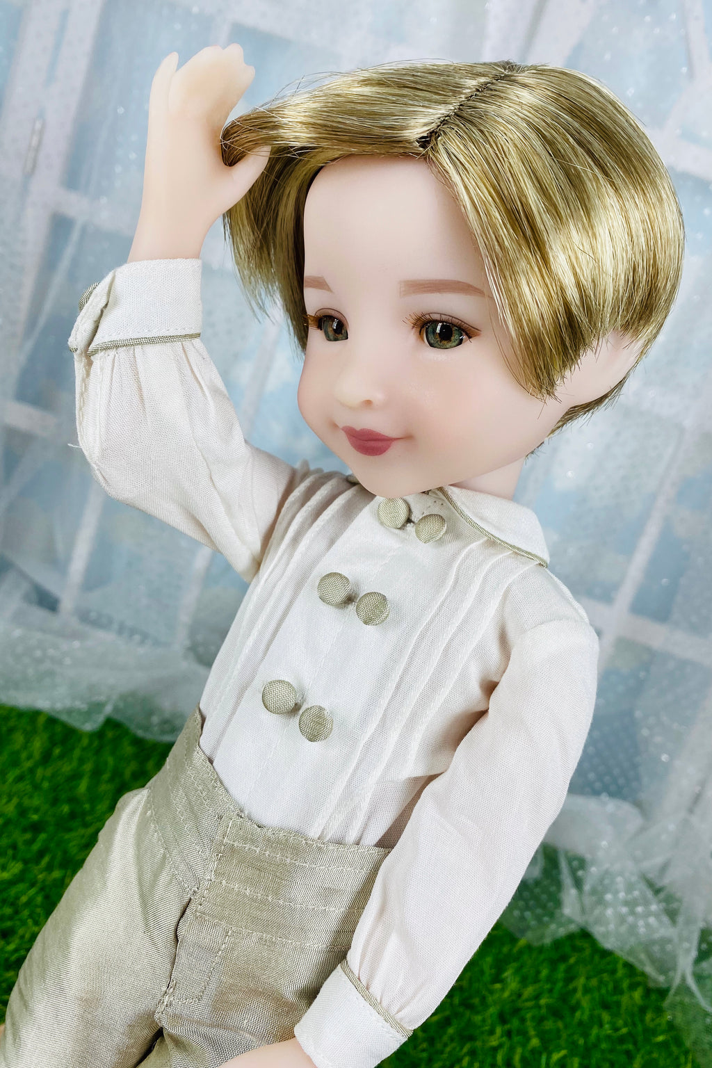 Doll with blonde hair and formal attire sitting on a grassy surface.