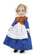 Doll in a blue dress with white apron and brown vest on a white background