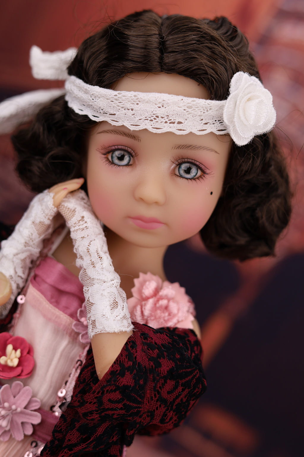 Detailed doll with lace headband and floral accessories against a blurred background