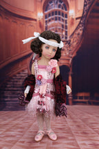 Doll in a vintage outfit with floral details standing in an elegant interior setting.