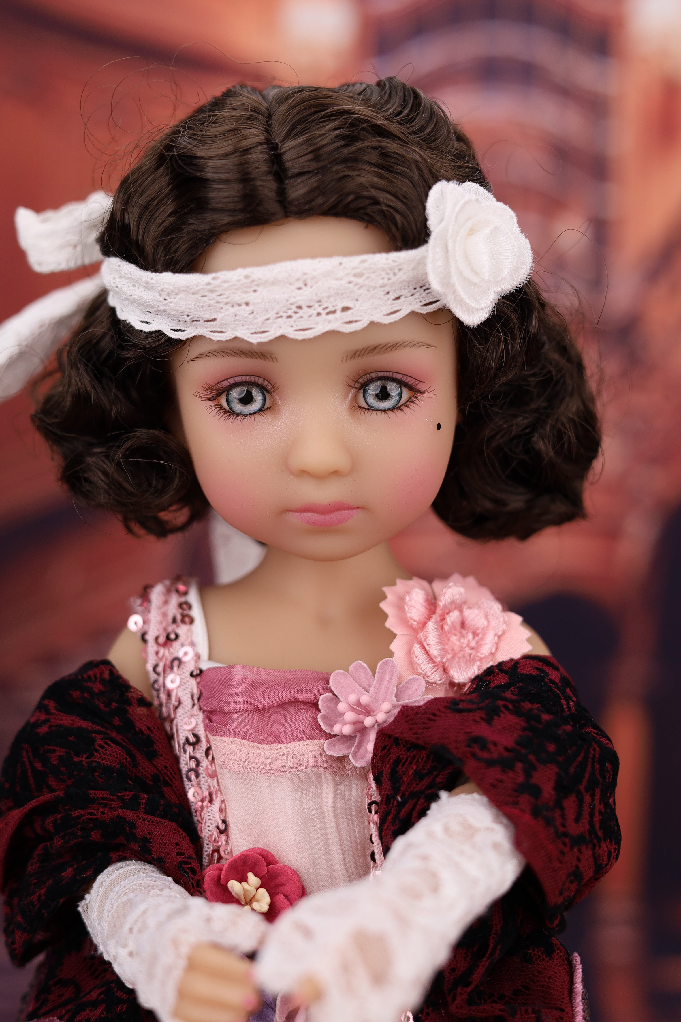 Doll with vintage-style clothing and headband against a blurred background