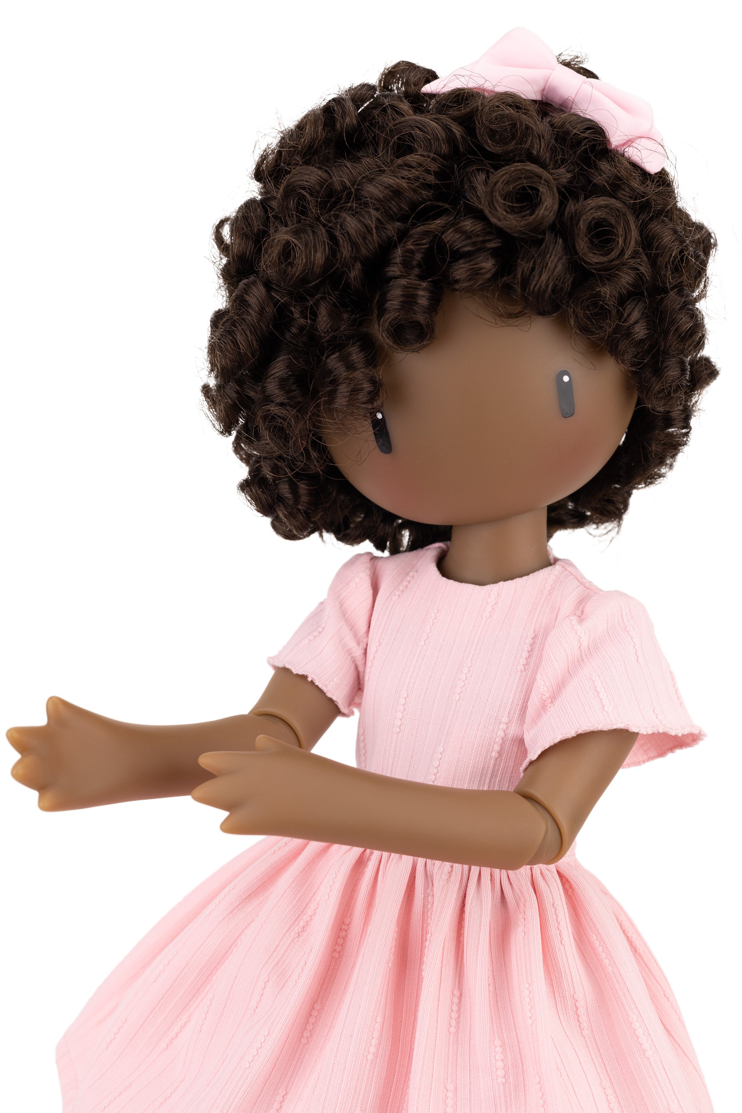 Doll with curly hair wearing a pink dress on a white background