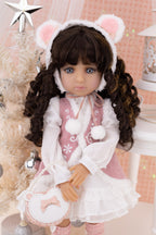 Doll in a festive outfit with bear ears and a pink dress, surrounded by Christmas decorations.