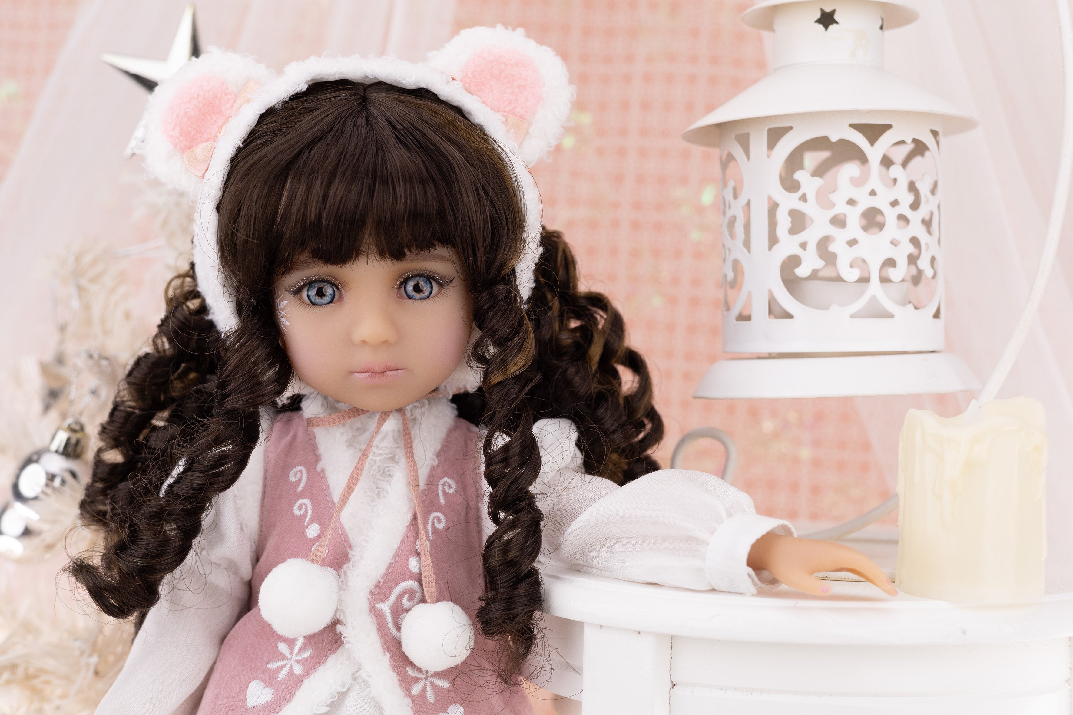 Doll with bear ears and pink outfit in a decorative setting