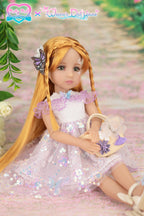 Doll in a pink dress with a butterfly hair accessory and floral bag, sitting on a pink surface with greenery.