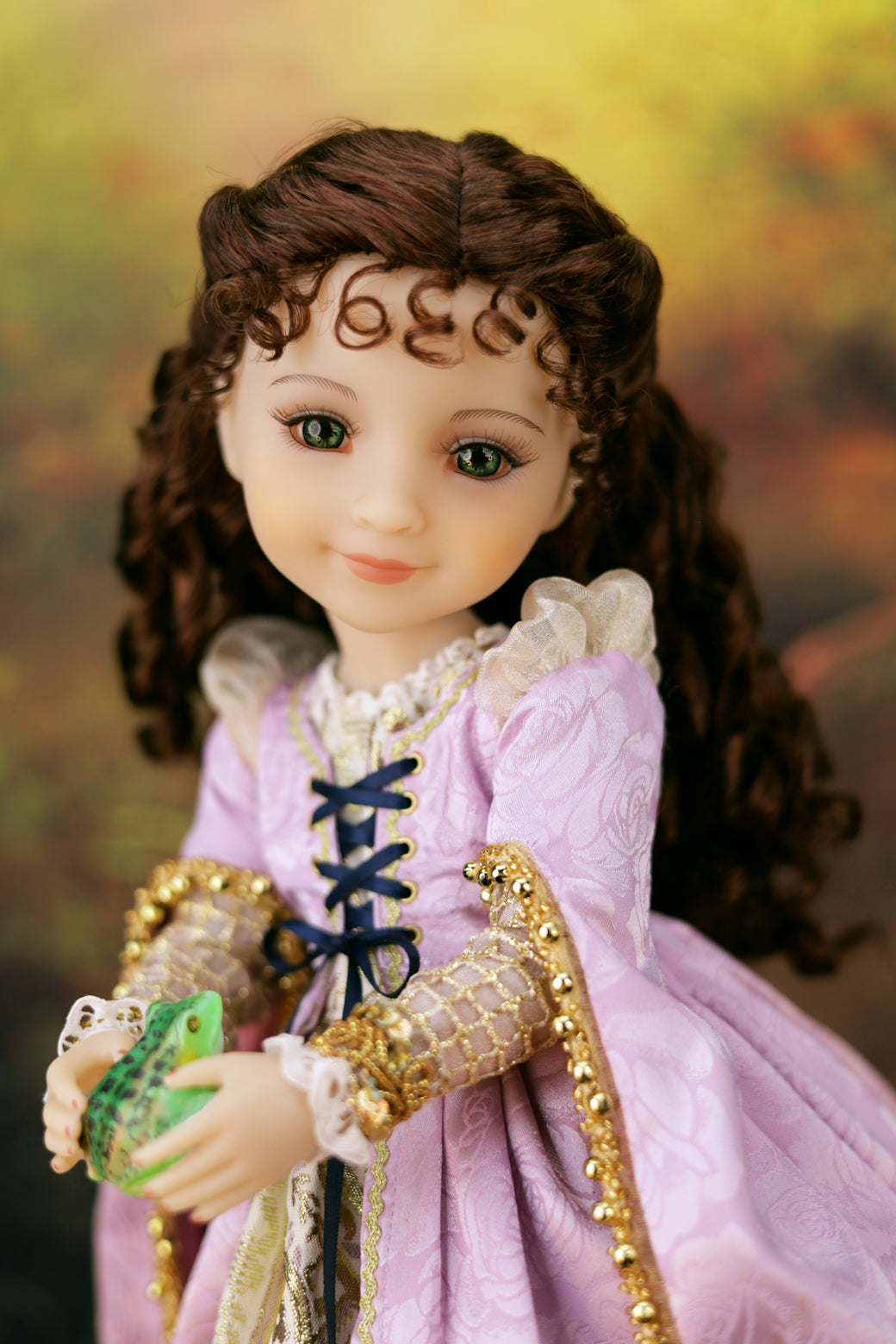 Princess Zora doll in a pink dress with gold accents and a green object, against a blurred background