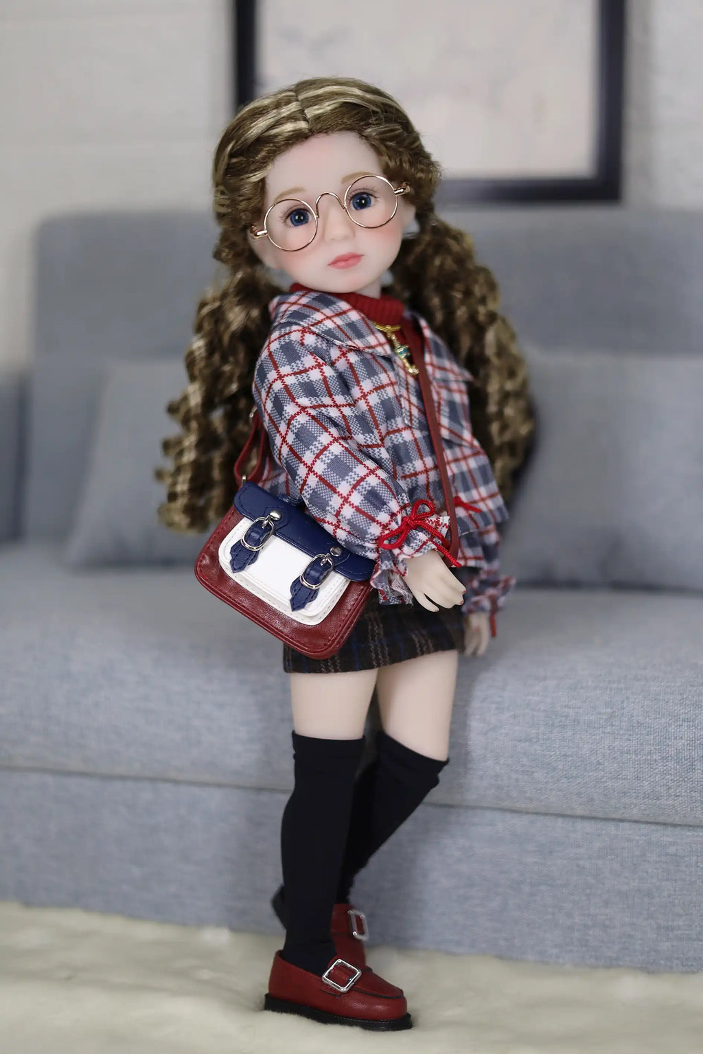 Doll with glasses and plaid outfit standing on a couch