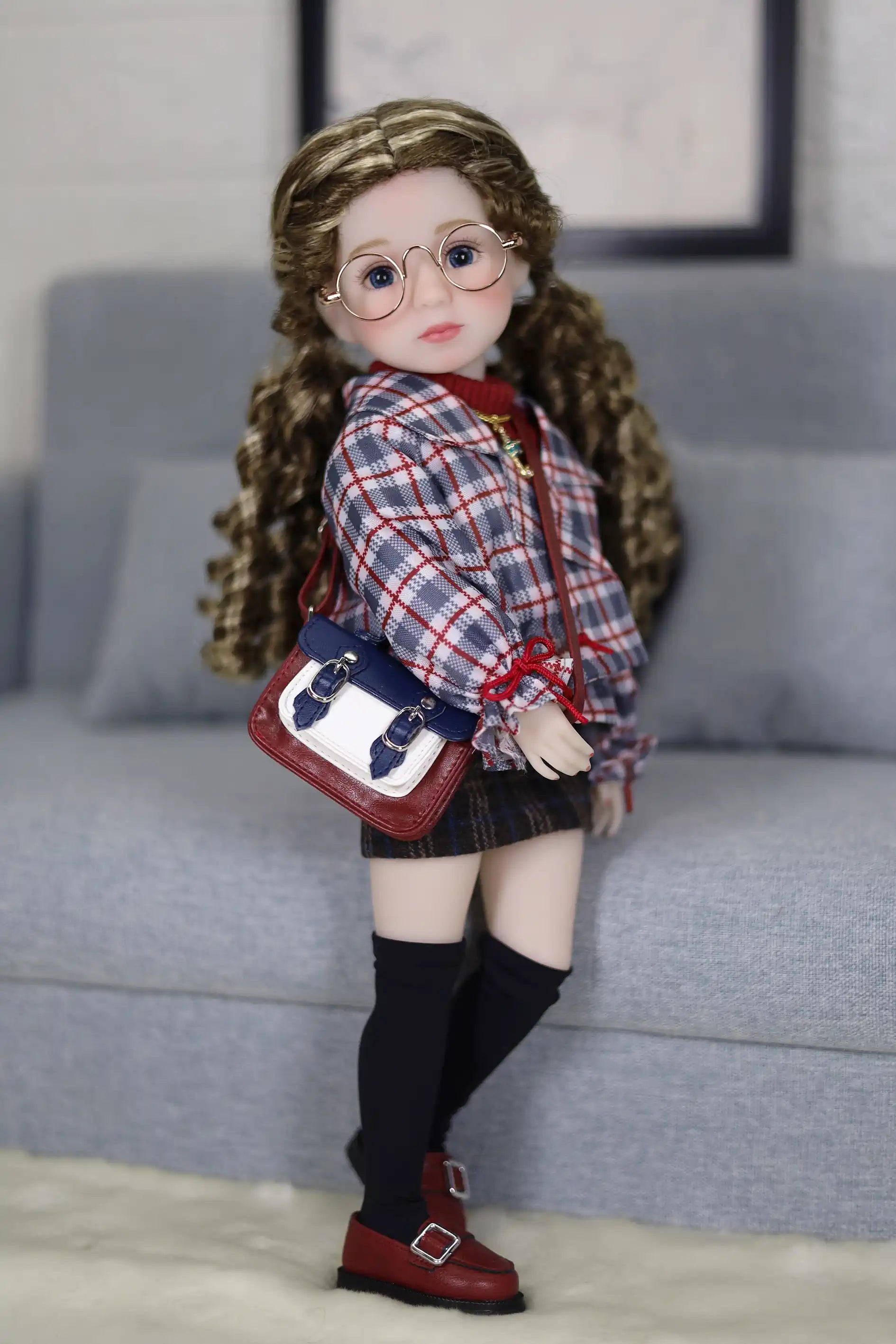 Doll with glasses and plaid outfit standing on a couch