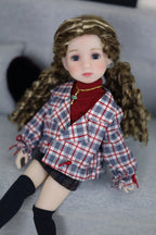 Doll wearing a plaid jacket and red sweater on a gray surface