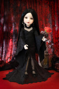 A gothic-style doll with long black hair, pale skin, and a black lace dress, holding a red rose against a dark red patterned curtain backdrop.
