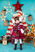 Doll in a festive outfit with a Christmas tree and decorations in the background