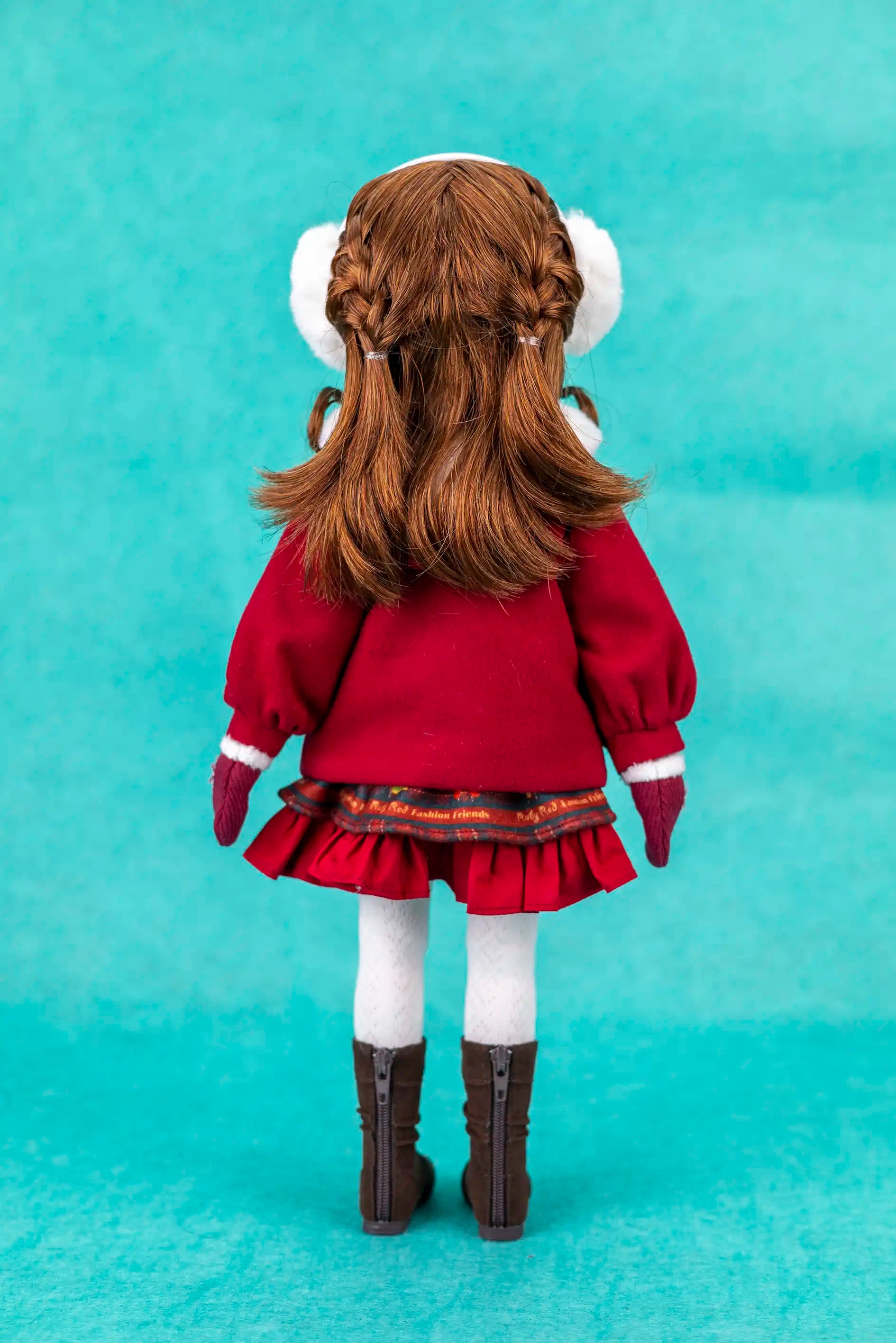 Doll in a red outfit with white earmuffs on a teal background