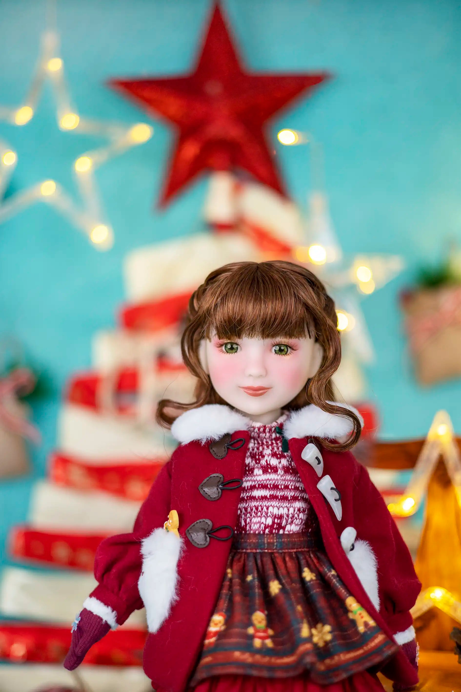 Doll in a festive outfit with a Christmas tree and star decoration in the background.