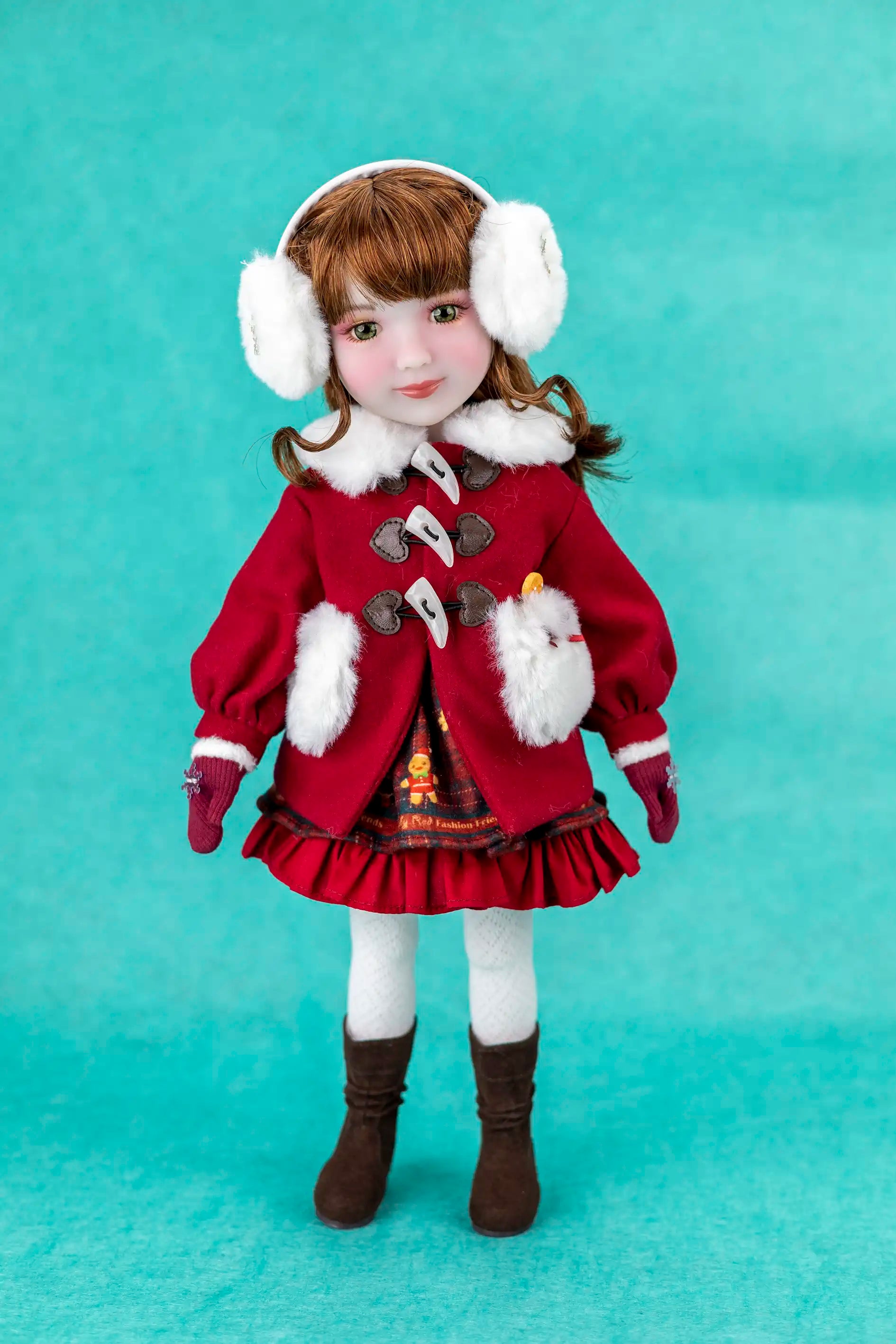 Doll wearing a red winter coat with white fur trim, white gloves, and brown boots on a teal background.
