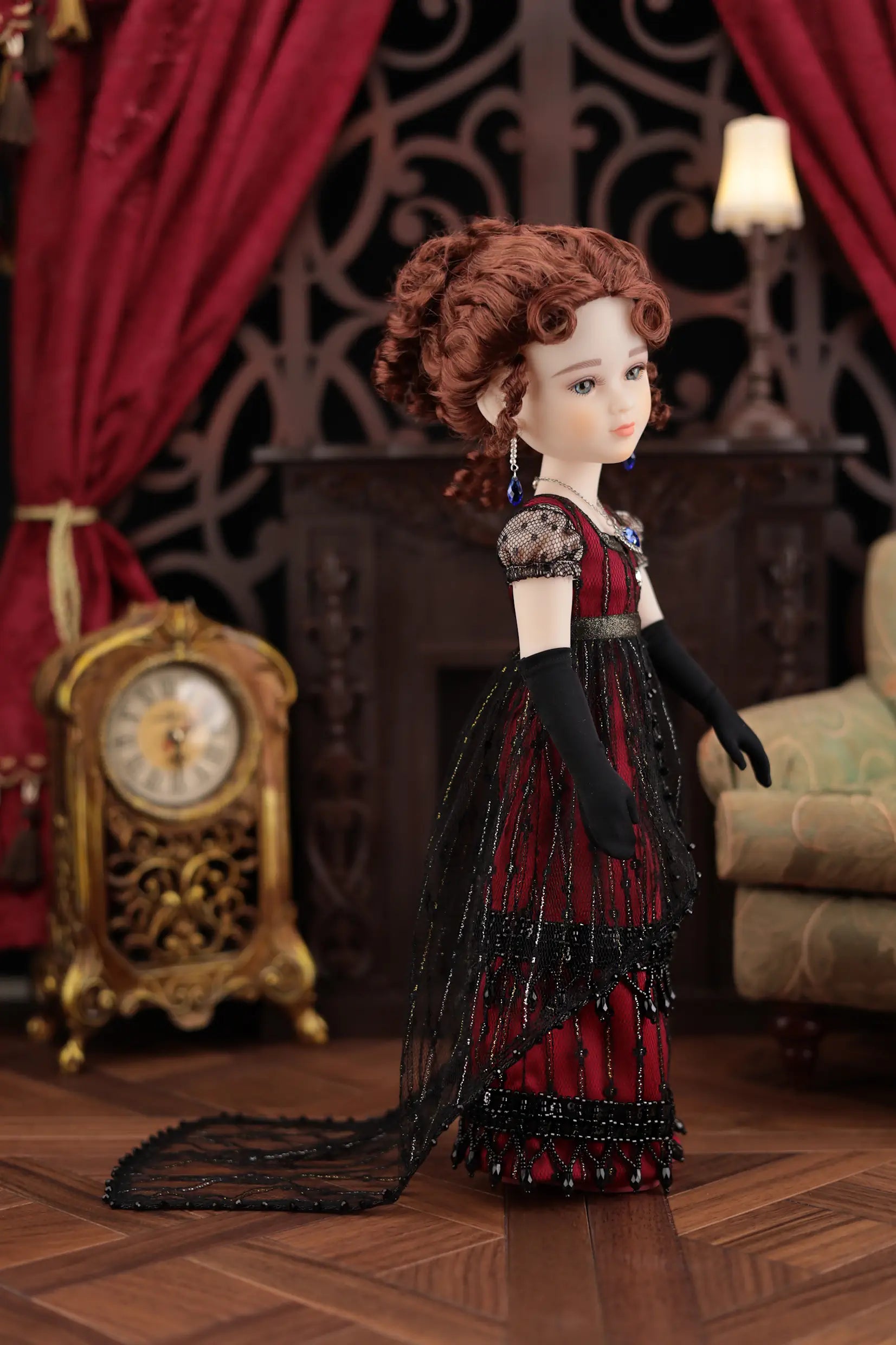 Doll in a vintage outfit standing in a room with red curtains and a clock.