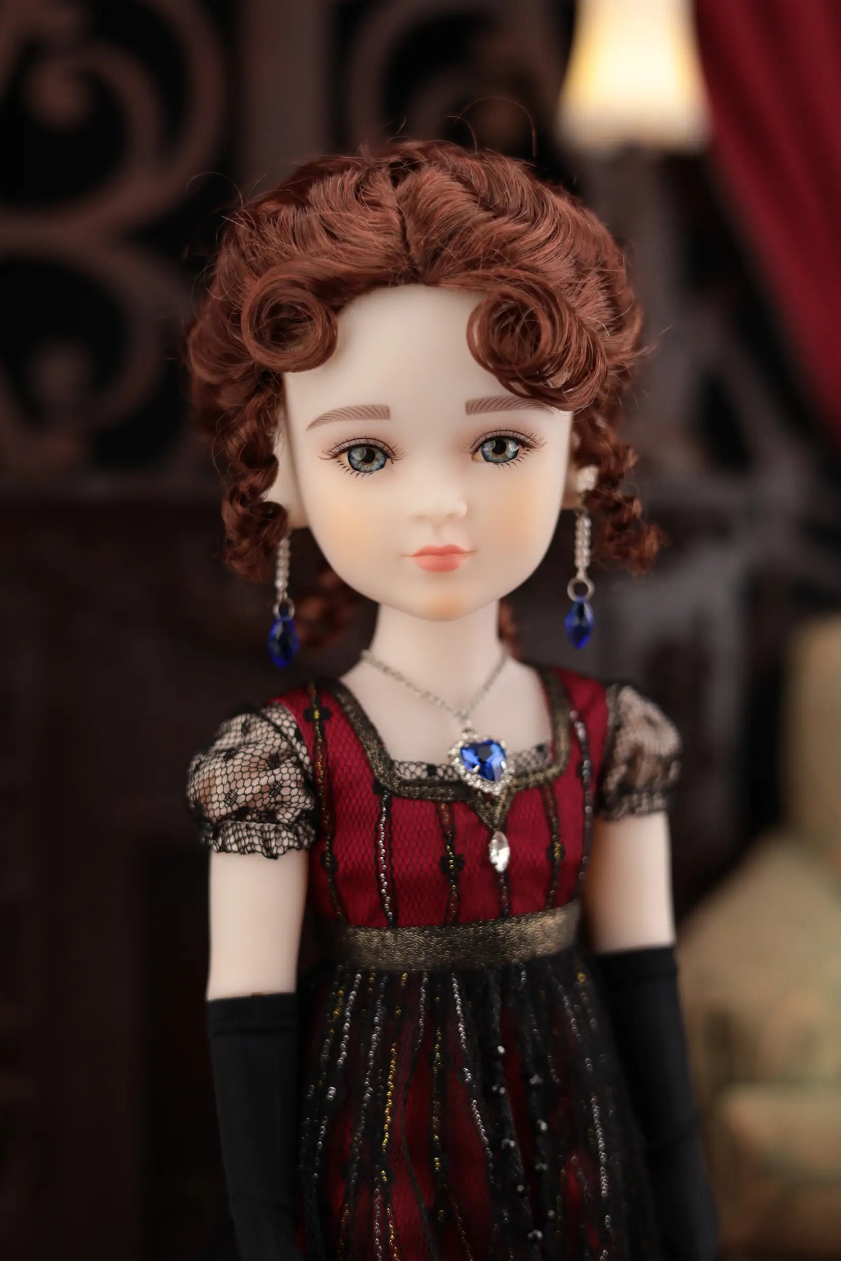 Doll with red and black outfit and jewelry against a blurred background