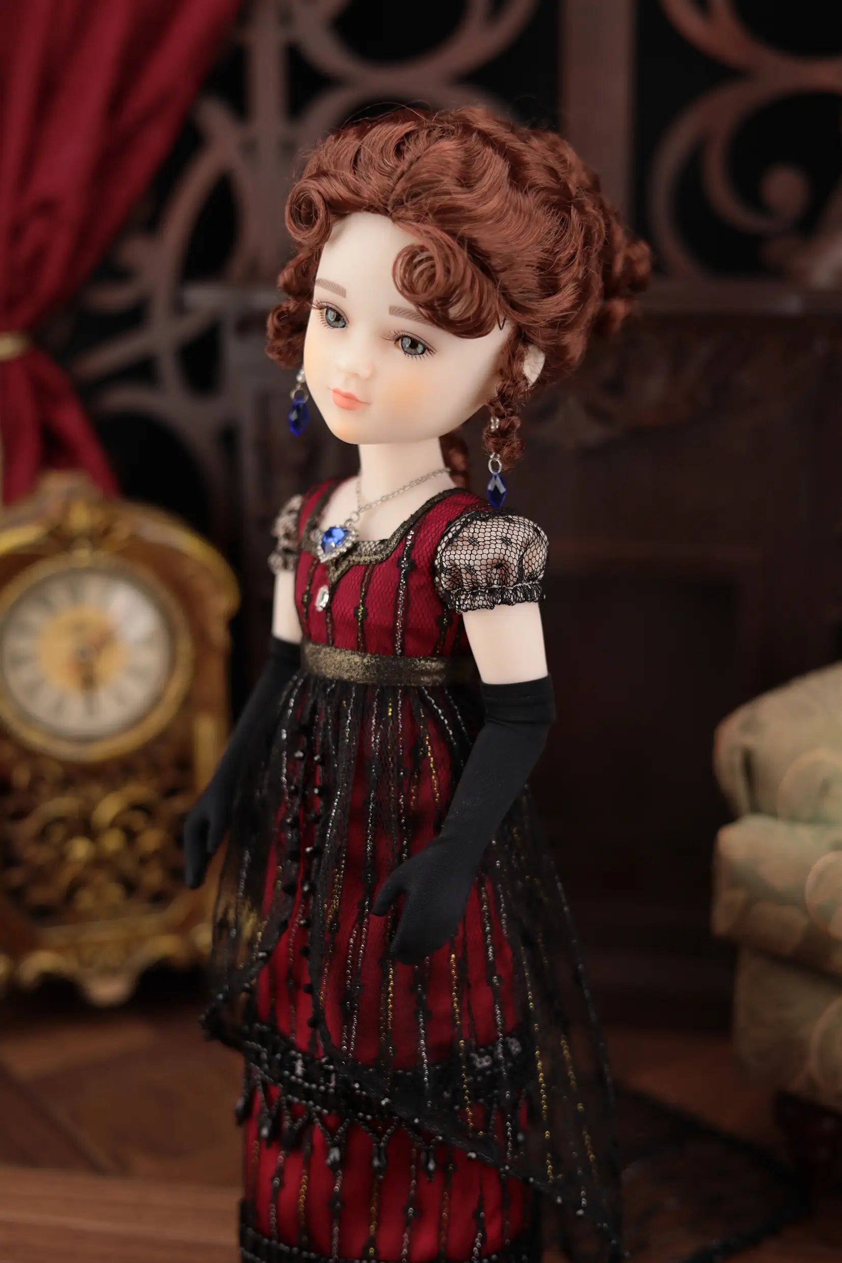 Vintage-style doll in a red dress with intricate details, standing in a decorative setting.
