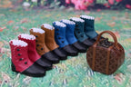 Row of colorful dog boots with a small suitcase on a textured surface