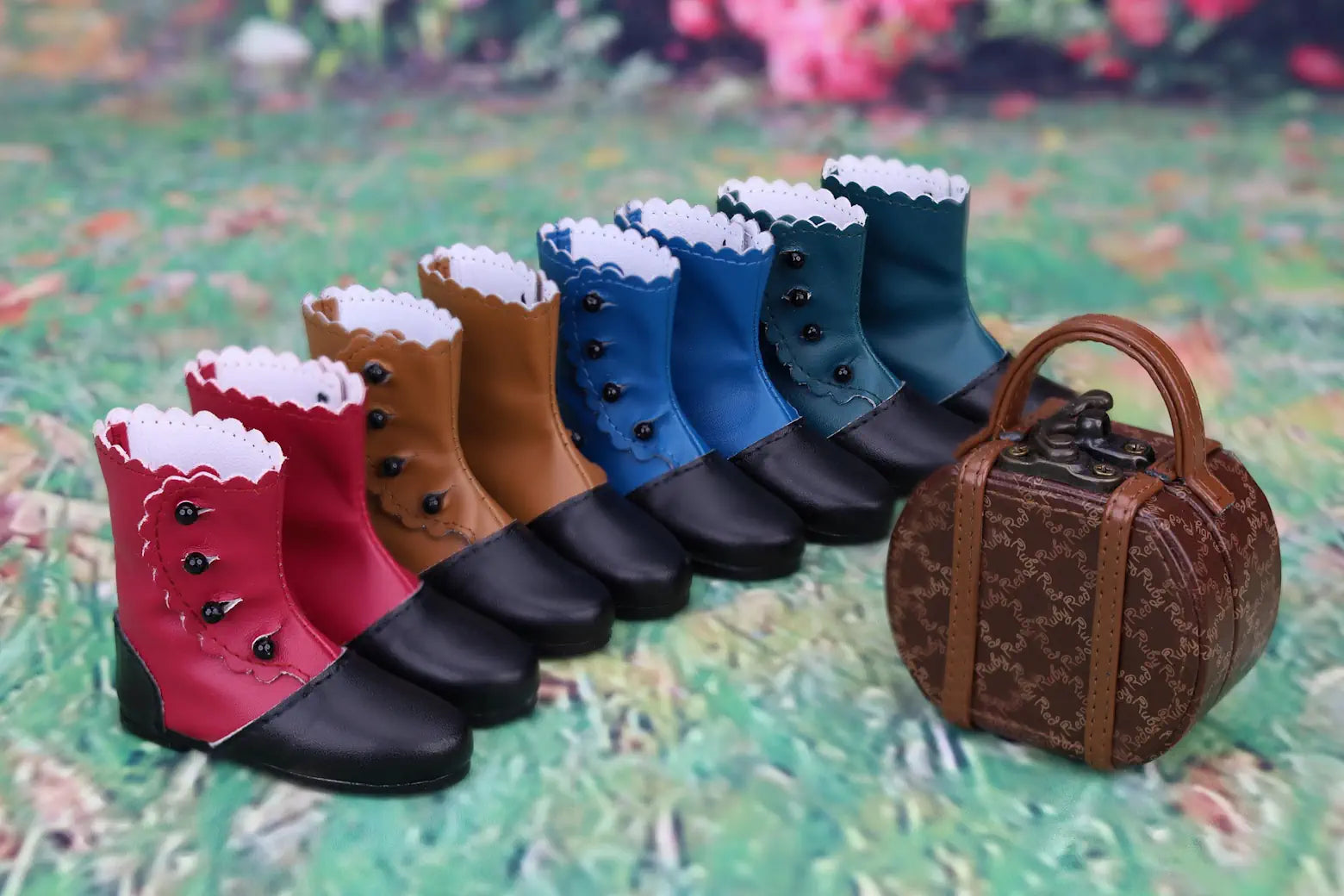 Row of colorful dog boots with a small suitcase on a textured surface