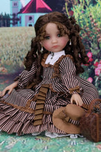 Doll in a vintage outfit with a hat and suitcase against a colorful background