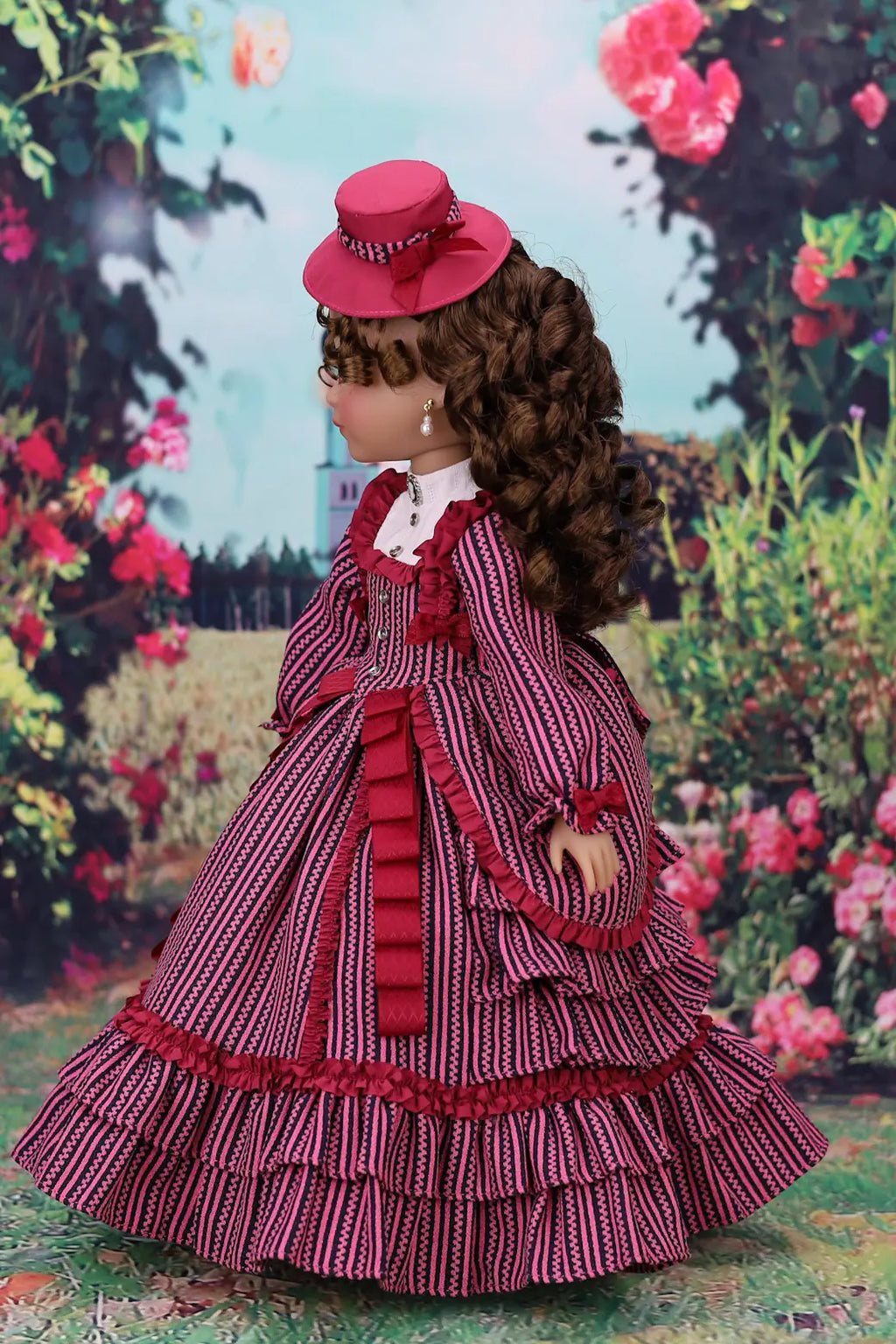 Doll in a red and white dress with a hat against a floral background